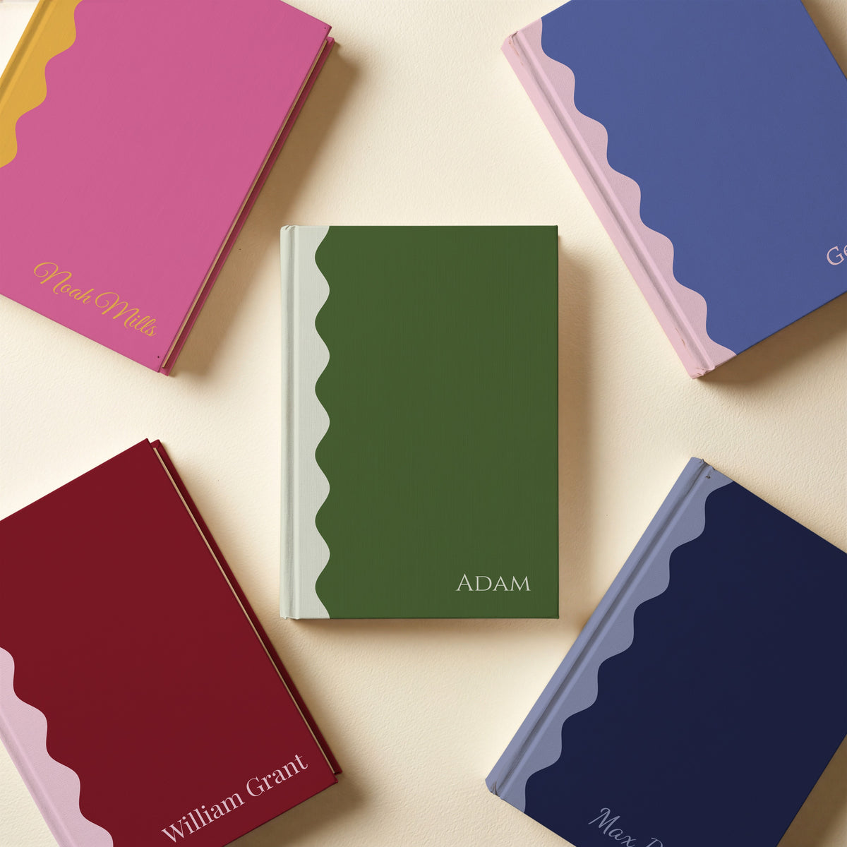 Five scalloped name notebooks laid flat in purple and blush, pink and mustard, burgundy and blush, navy and periwinkle, green and cream