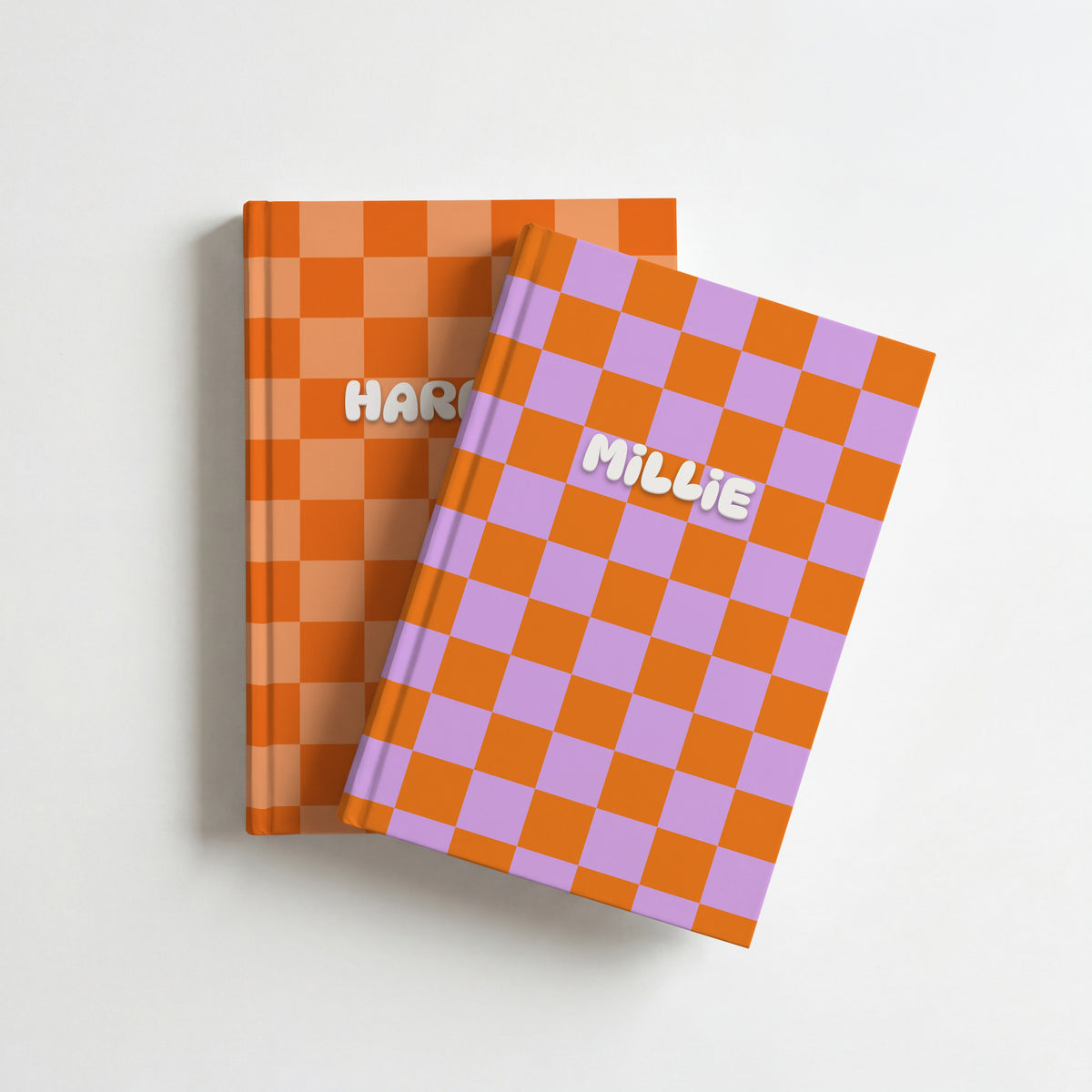 Two personalised checkerboard notebooks, orange and lilac with the name Millie on top of tangerine