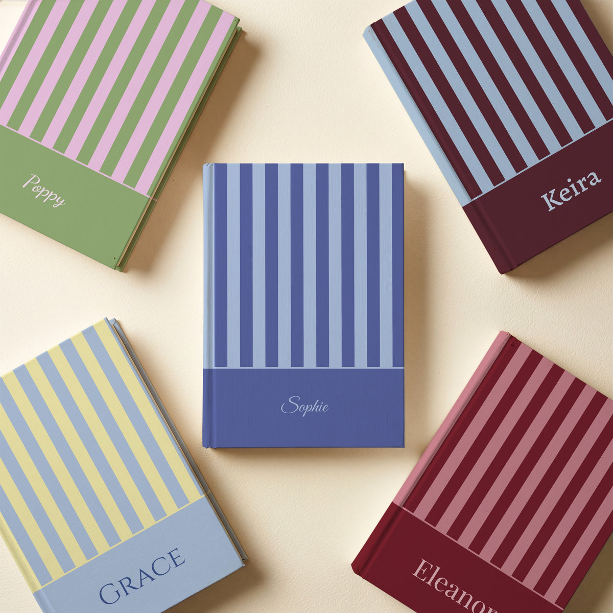 Five personalised stripe and colour band notebooks in blue, maroon, strawberry matcha, blue and yellow, and burgundy