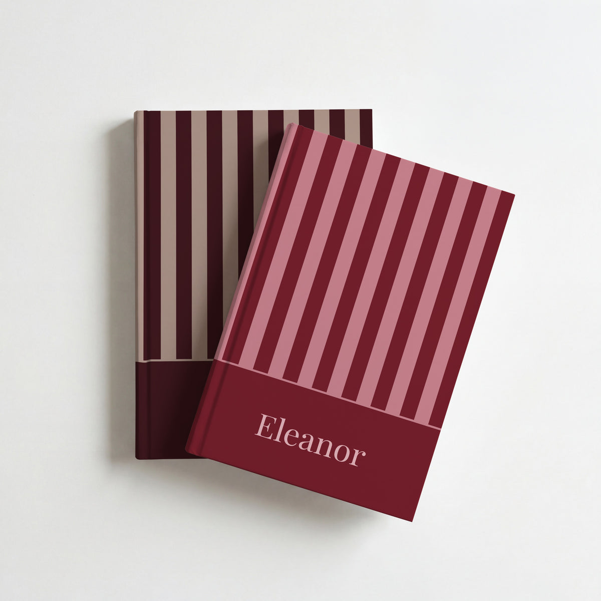 Two personalised striped notebooks, burgundy with the name Eleanor on top of brown and taupe