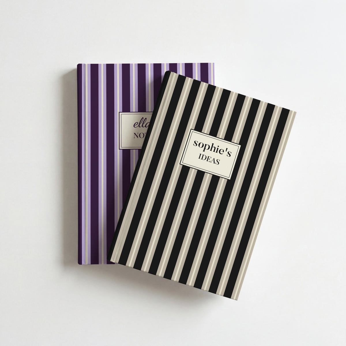 Two personalised striped notebooks, black and stone reading sophie's Ideas on top of plum and lilac