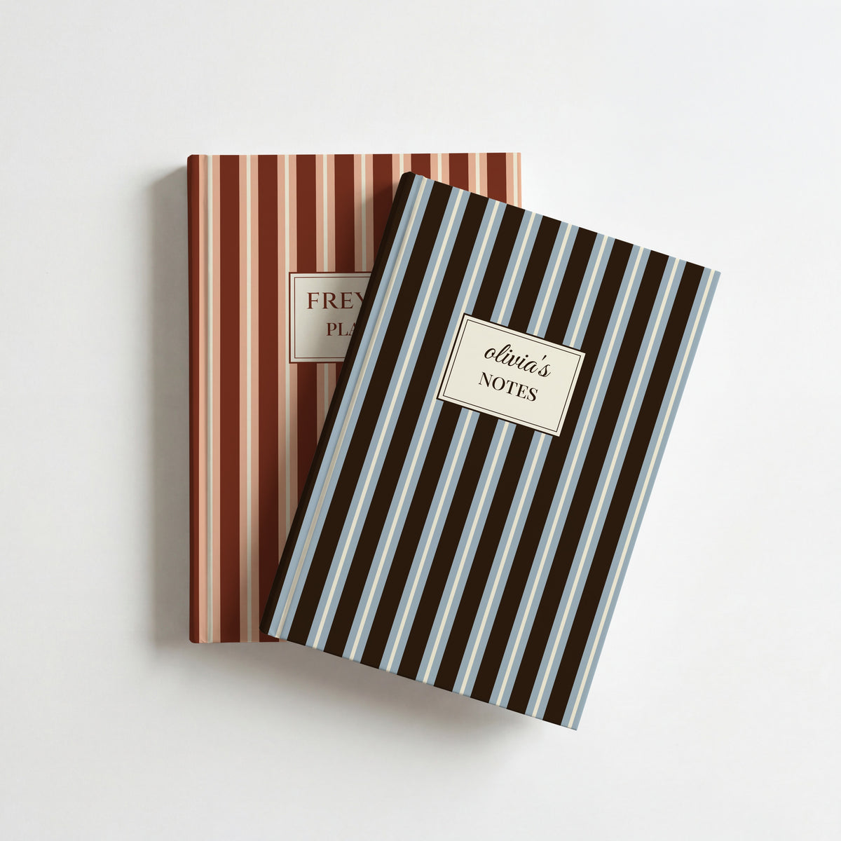 Two personalised striped notebooks, chocolate and powder blue reading olivia's Notes on top of terracotta and peach