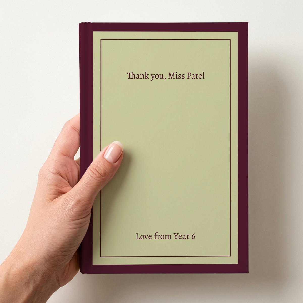 Hand holding a personalised pistachio notebook with a plum border reading Thank you, Miss Patel and Love from Year 6