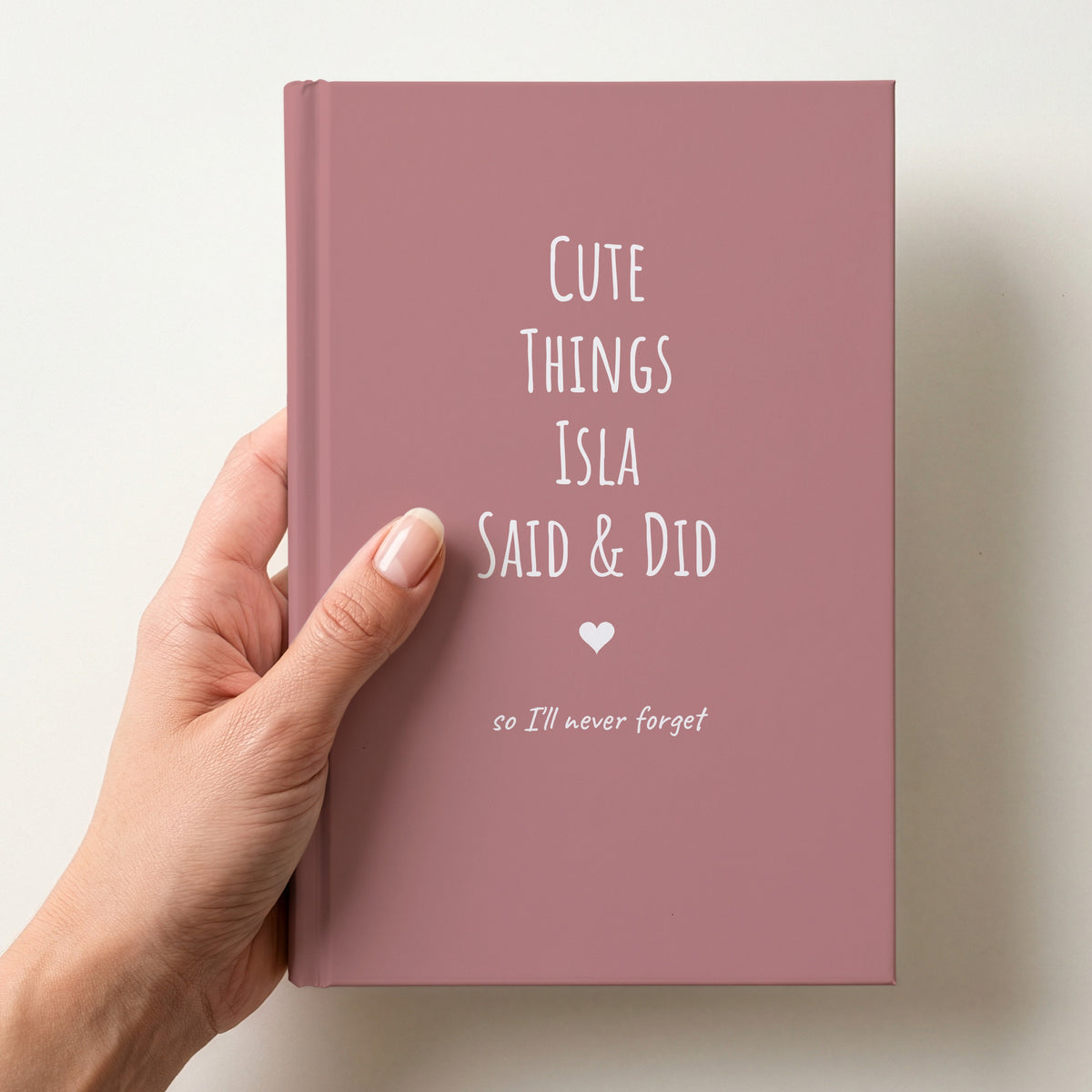 Hand holding a dusty rose personalised journal reading Cute Things Isla Said & Did