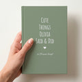 Hand holding a sage green personalised journal reading Cute Things Olivia Said & Did, with a heart and so I'll never forget