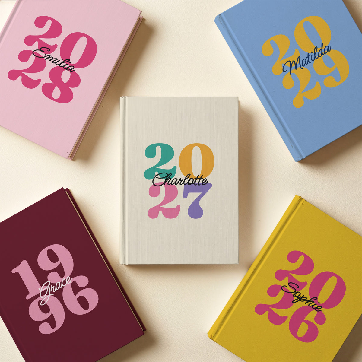 Five personalised retro year journals for 2027, 2028, 2029, 2026 and 1996 in ivory, pink, sky blue, mustard and burgundy