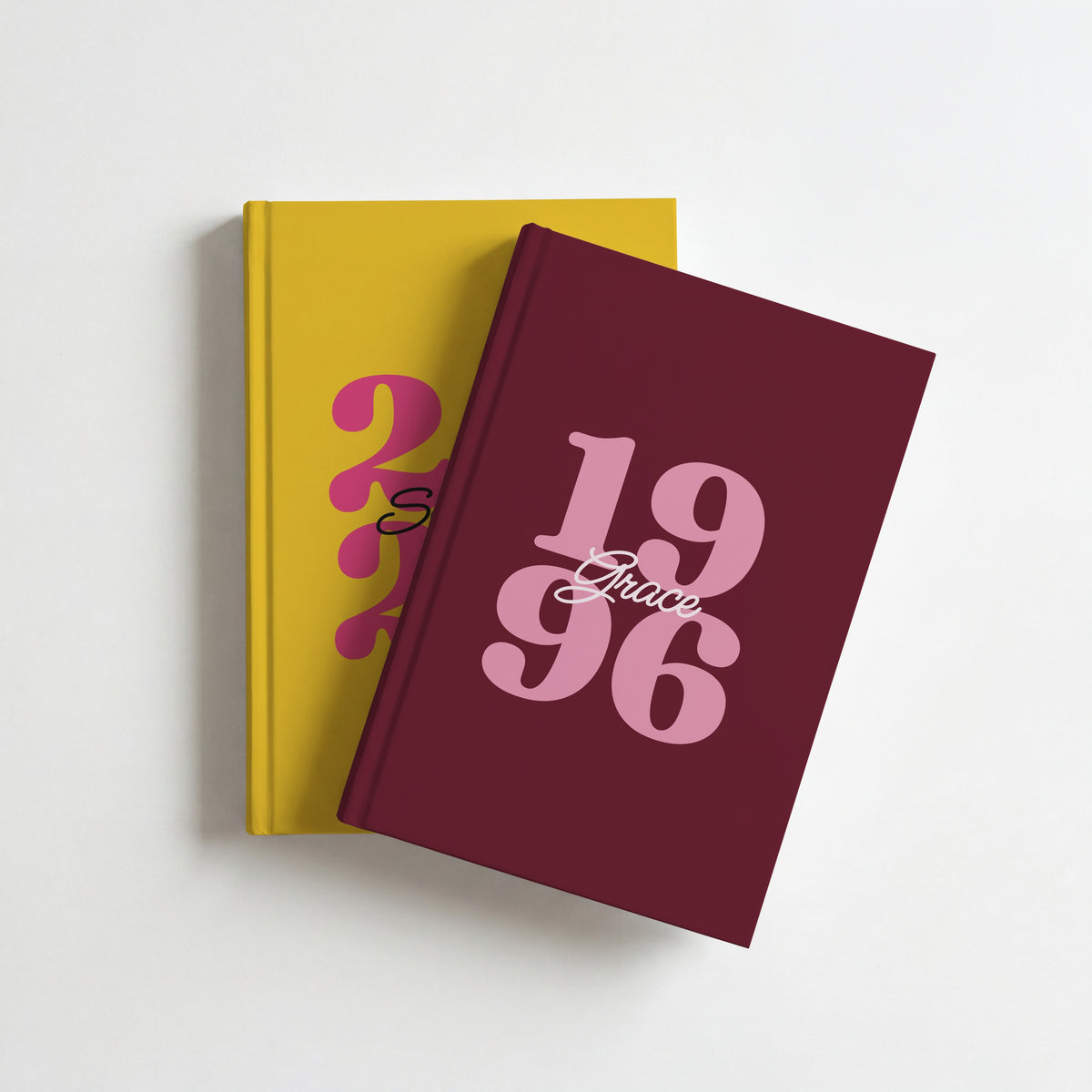 Two personalised year journals, burgundy 1996 for Grace on top of mustard 2026