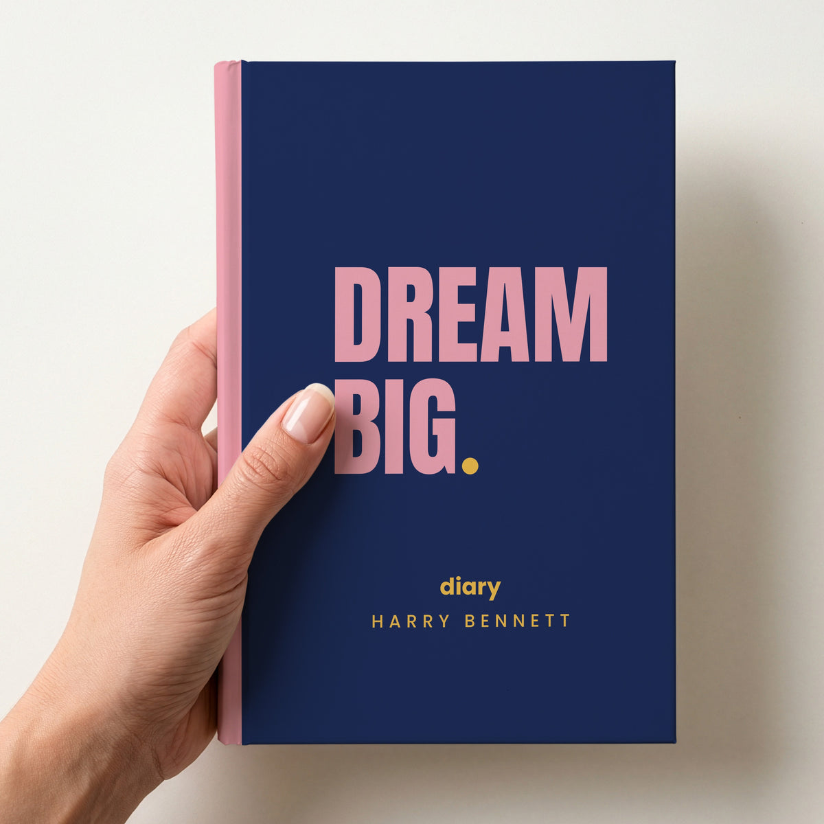 Hand holding a navy personalised notebook with 'DREAM BIG.' in pink and 'diary' and the name Harry Bennett below