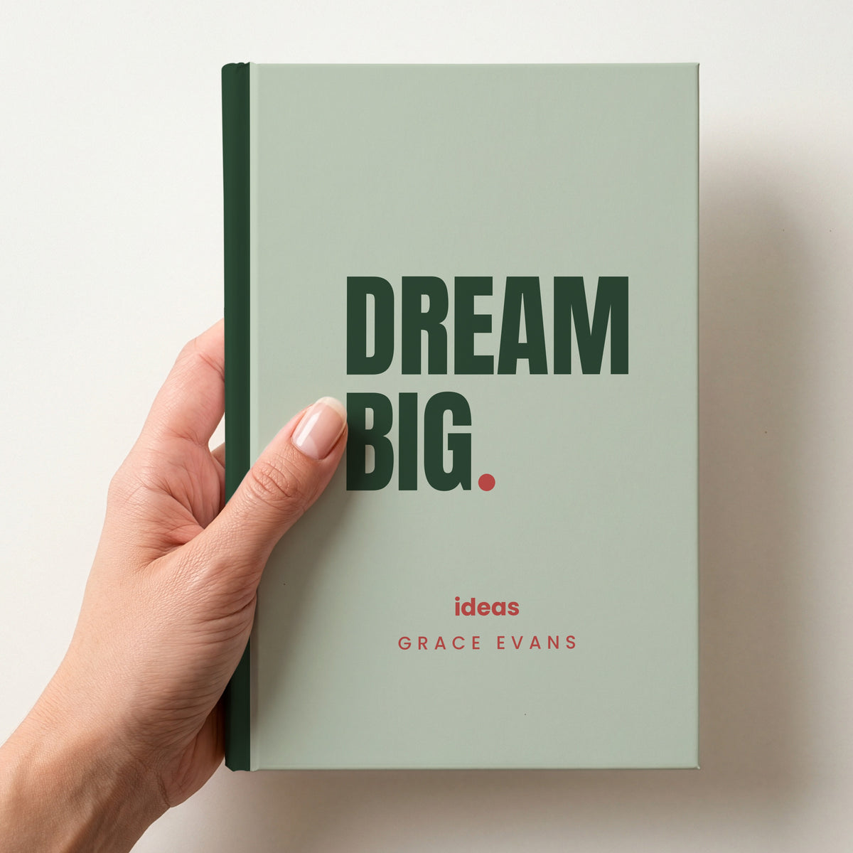 Hand holding a sage personalised notebook with 'DREAM BIG.' in forest and 'ideas' and the name Grace Evans below