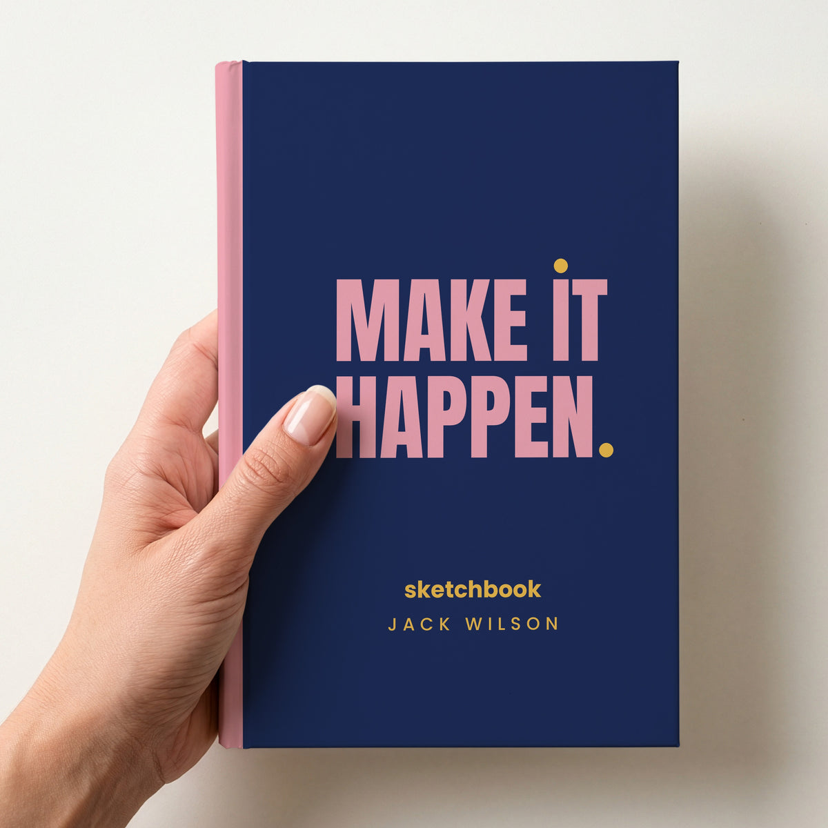Hand holding a navy personalised notebook with 'MAKE IT HAPPEN.' in pink and 'sketchbook' and the name Jack Wilson below