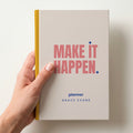 Hand holding a oat personalised notebook with 'MAKE IT HAPPEN.' in coral and 'planner' and the name Grace Evans below
