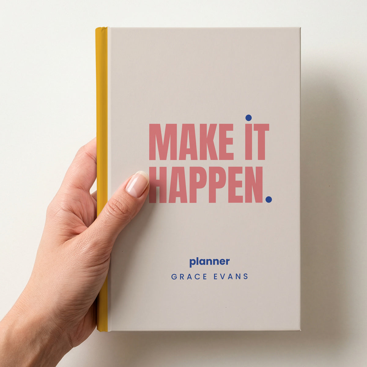 Hand holding a oat personalised notebook with 'MAKE IT HAPPEN.' in coral and 'planner' and the name Grace Evans below