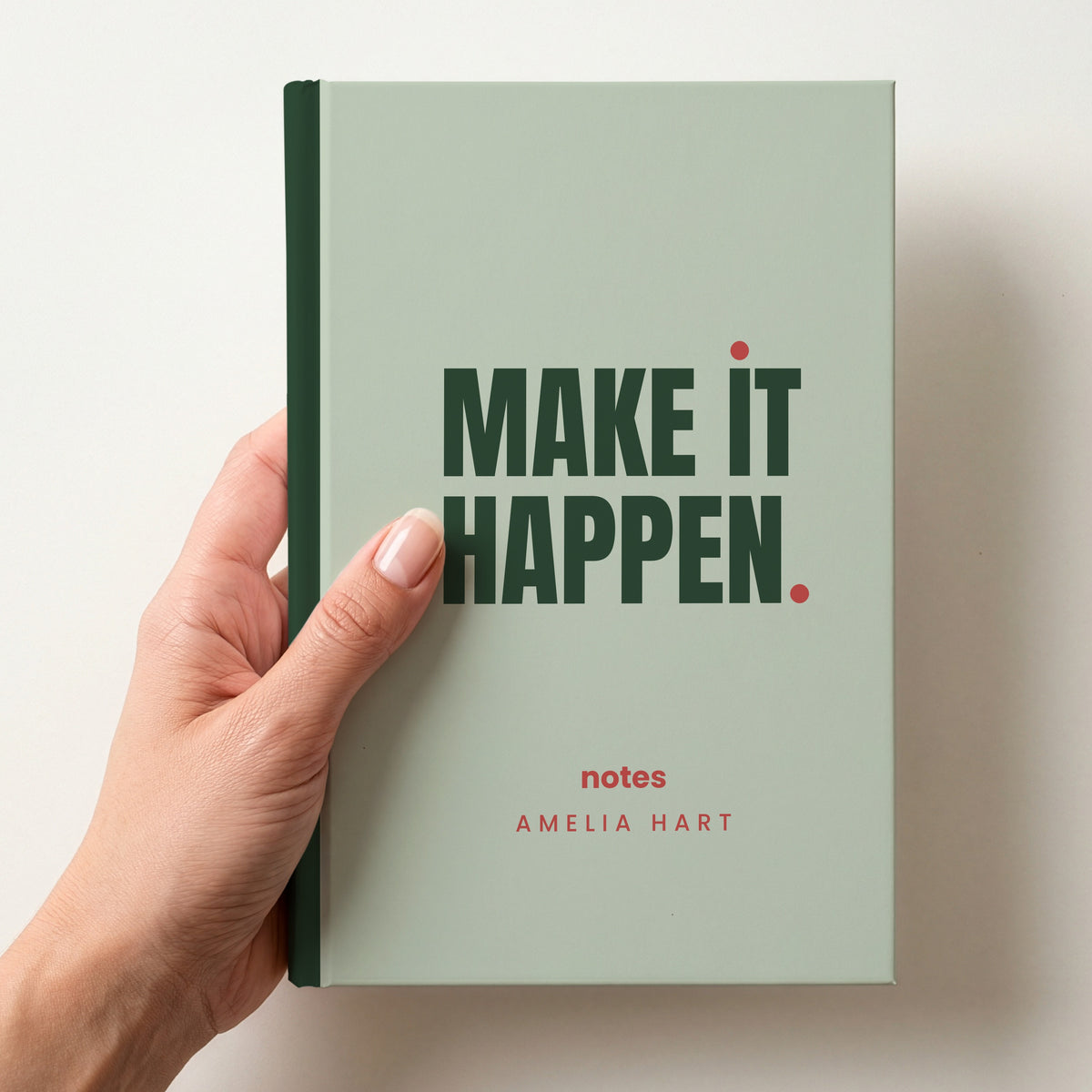Hand holding a sage personalised notebook with 'MAKE IT HAPPEN.' in forest and 'notes' and the name Amelia Hart below