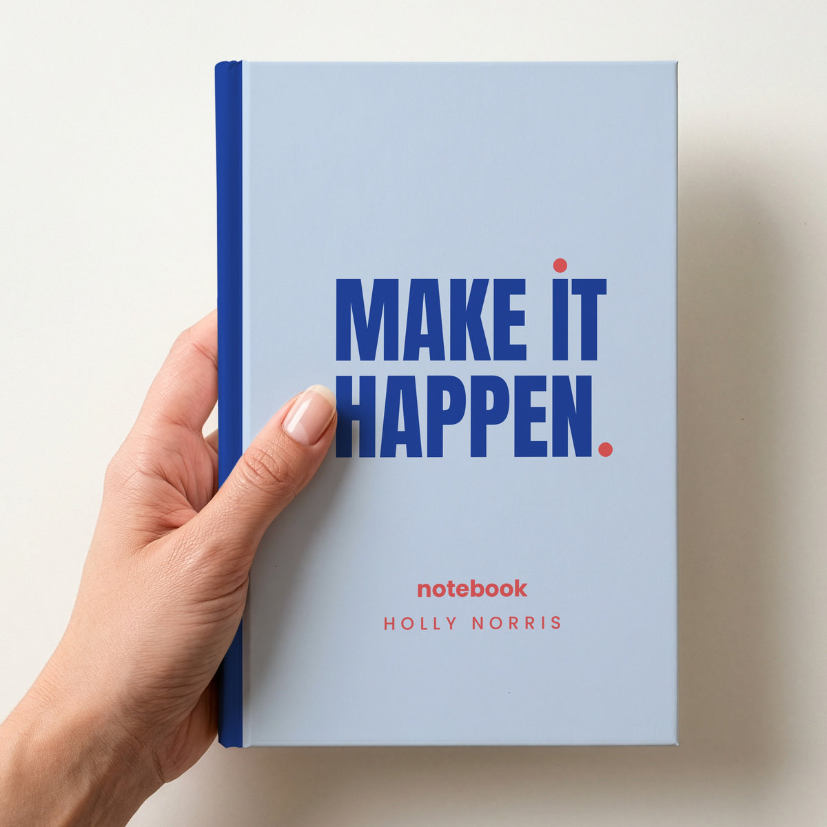 Hand holding a sky personalised notebook with 'MAKE IT HAPPEN.' in cobalt and 'notebook' and the name Holly Norris below