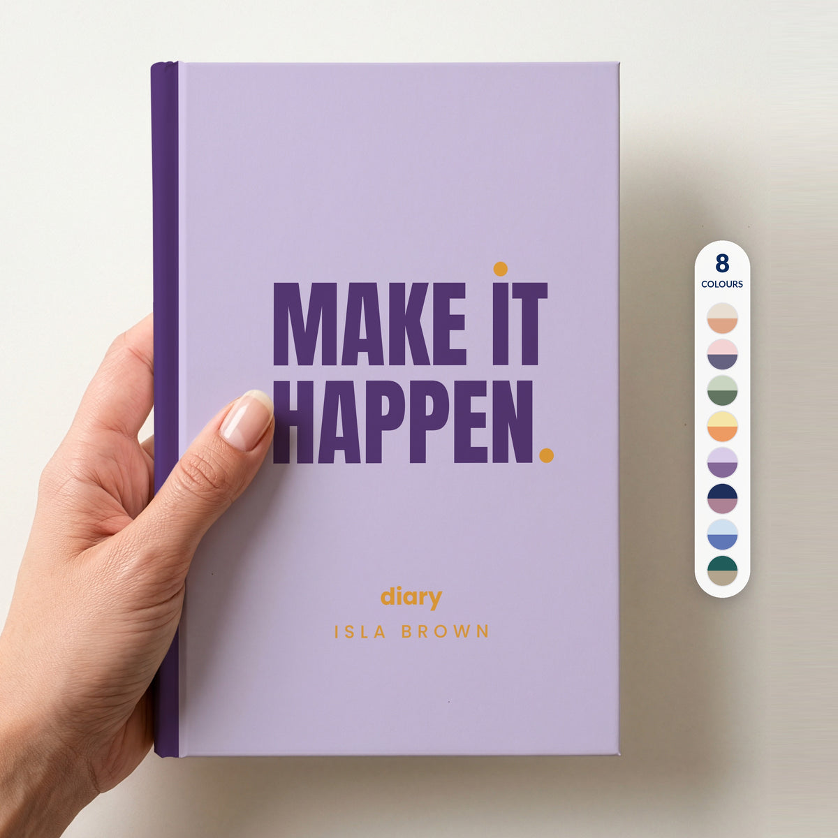 Hand holding a lilac personalised notebook with 'MAKE IT HAPPEN.' in plum and 'diary' and the name Isla Brown below, beside a column of 8 colour swatches showing all 8 colourways