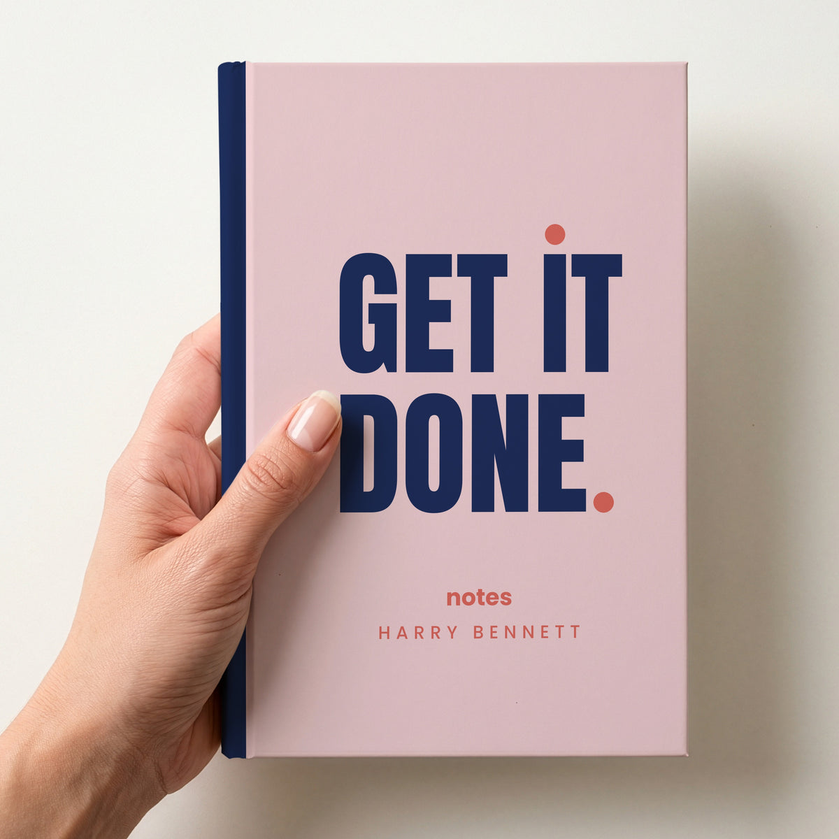 Hand holding a blush personalised notebook with 'GET IT DONE.' in navy and 'notes' and the name Harry Bennett below