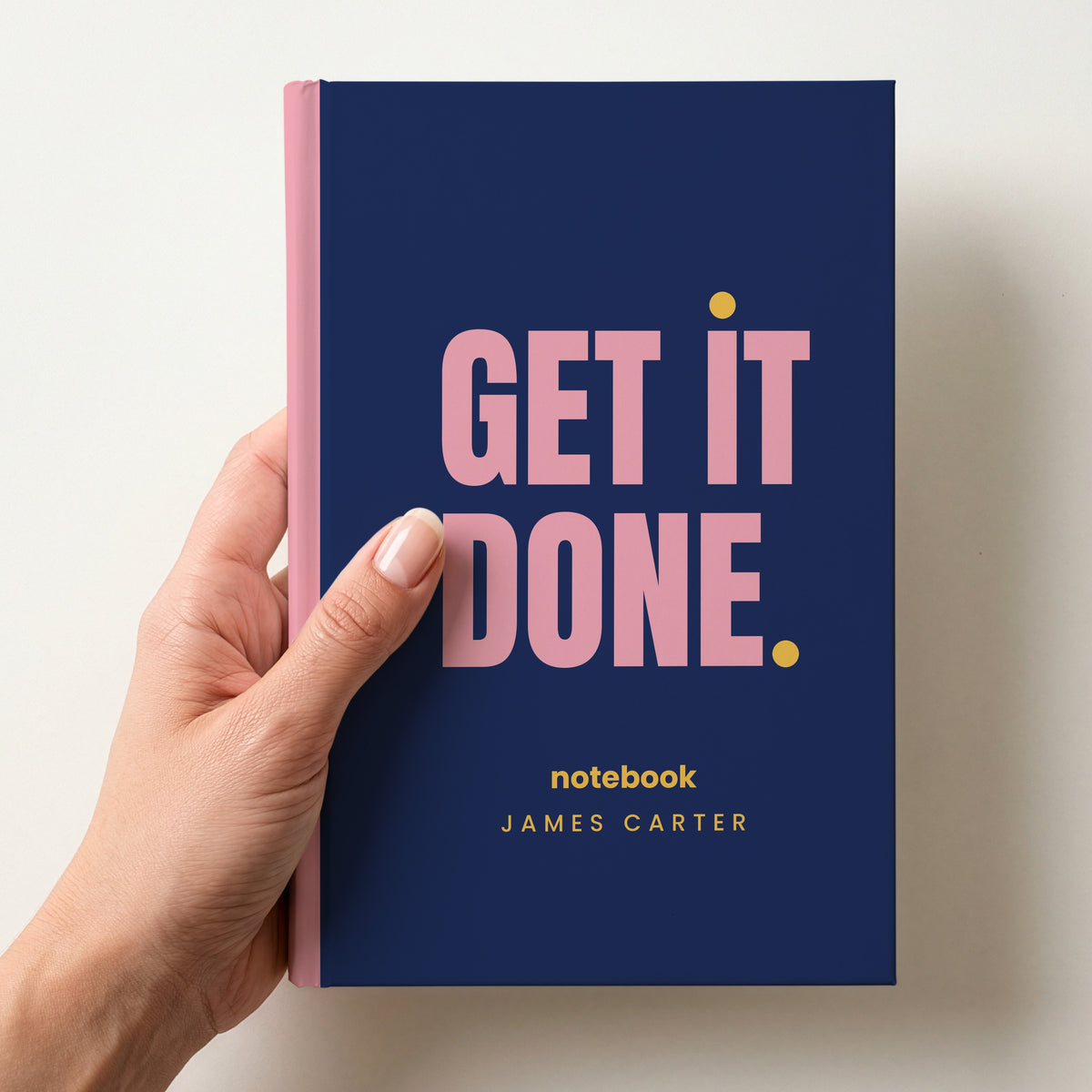 Hand holding a navy personalised notebook with 'GET IT DONE.' in pink and 'notebook' and the name James Carter below