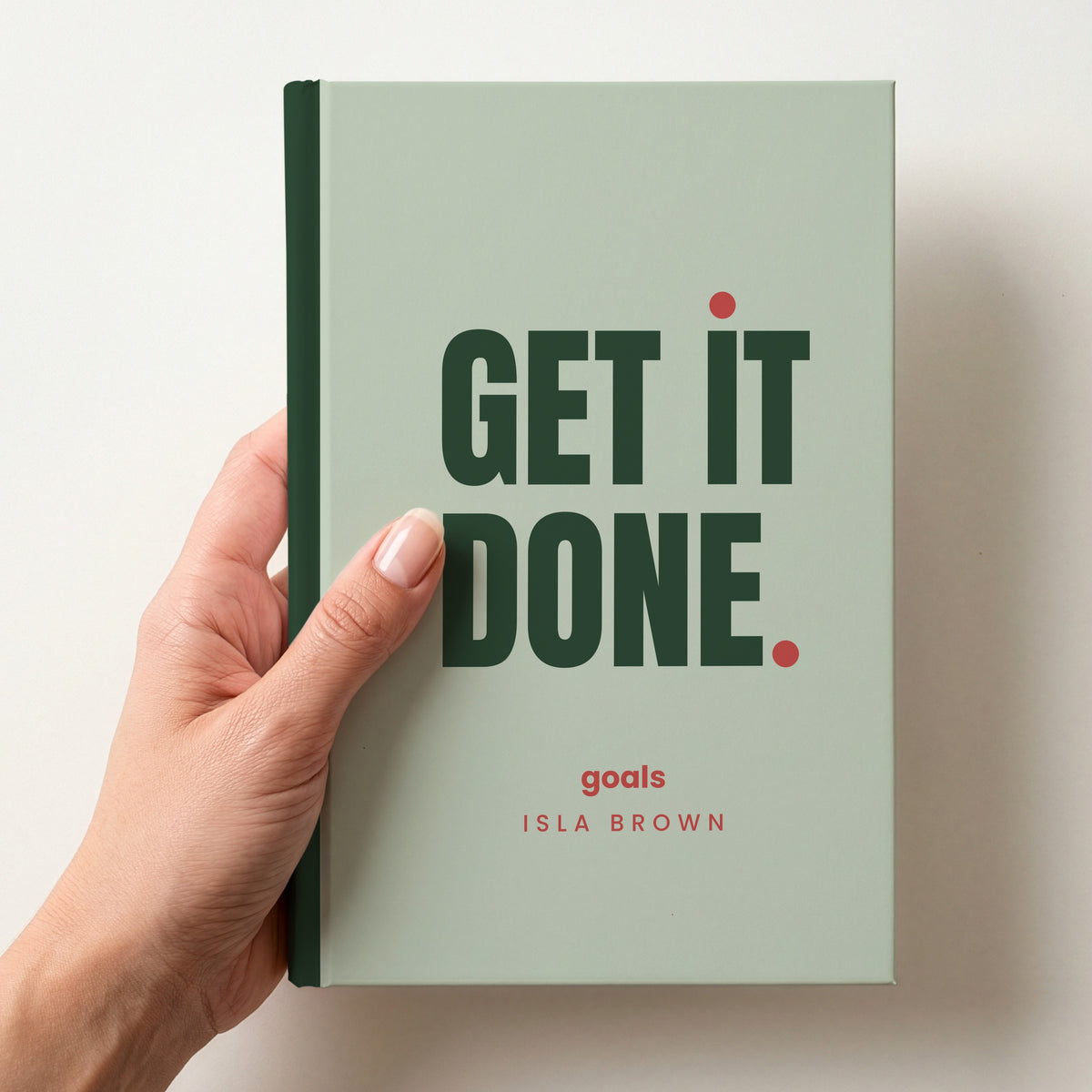 Hand holding a sage personalised notebook with 'GET IT DONE.' in forest and 'goals' and the name Isla Brown below