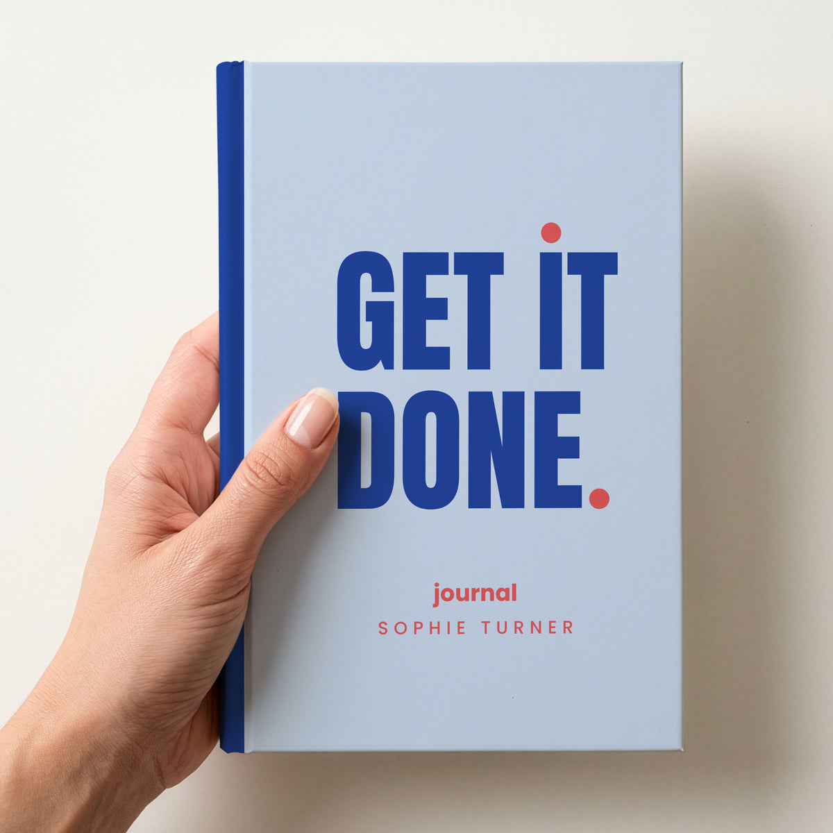 Hand holding a sky personalised notebook with 'GET IT DONE.' in cobalt and 'journal' and the name Sophie Turner below