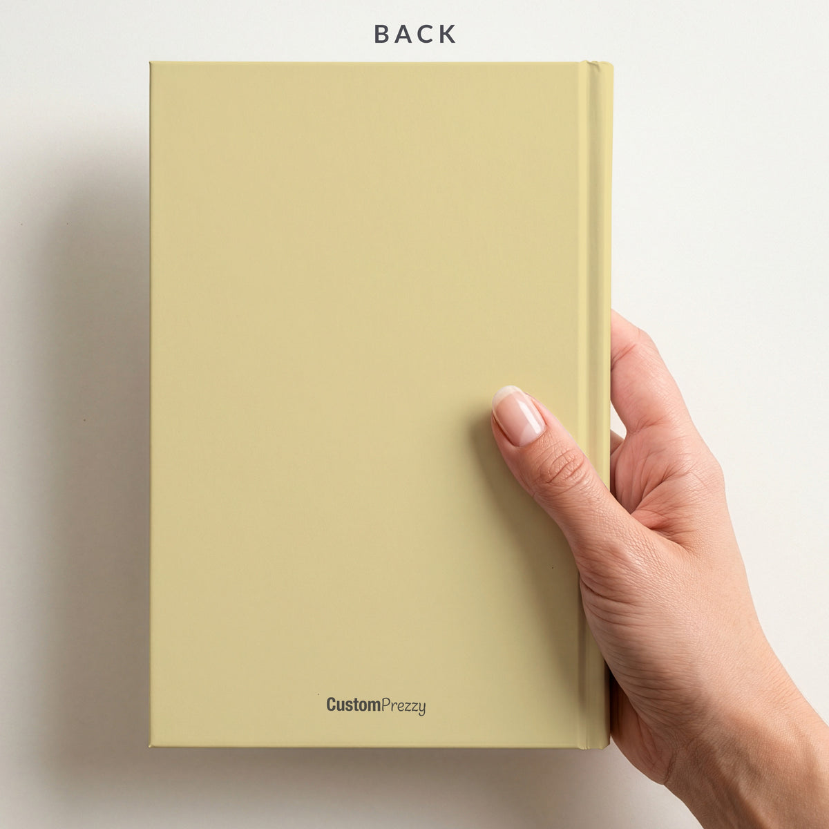 Back of the butter notebook held in a hand, with the Custom Prezzy wordmark at the foot