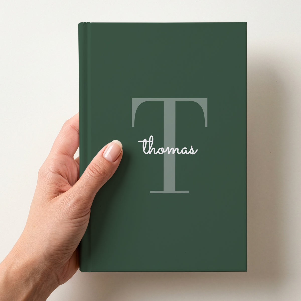 Hand holding a forest personalised journal with a large T initial and the name thomas in script