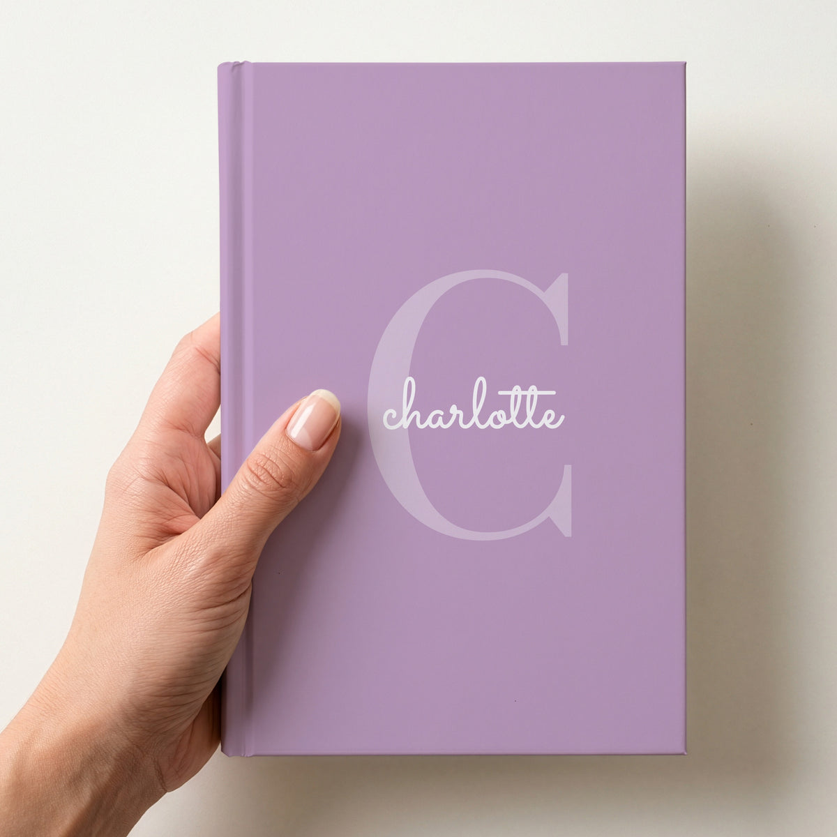 Hand holding a lavender personalised journal with a large C initial and the name charlotte in script