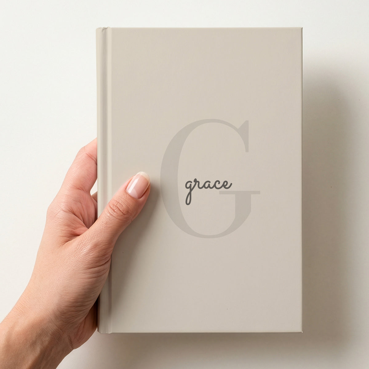 Hand holding a oatmeal personalised journal with a large G initial and the name grace in script