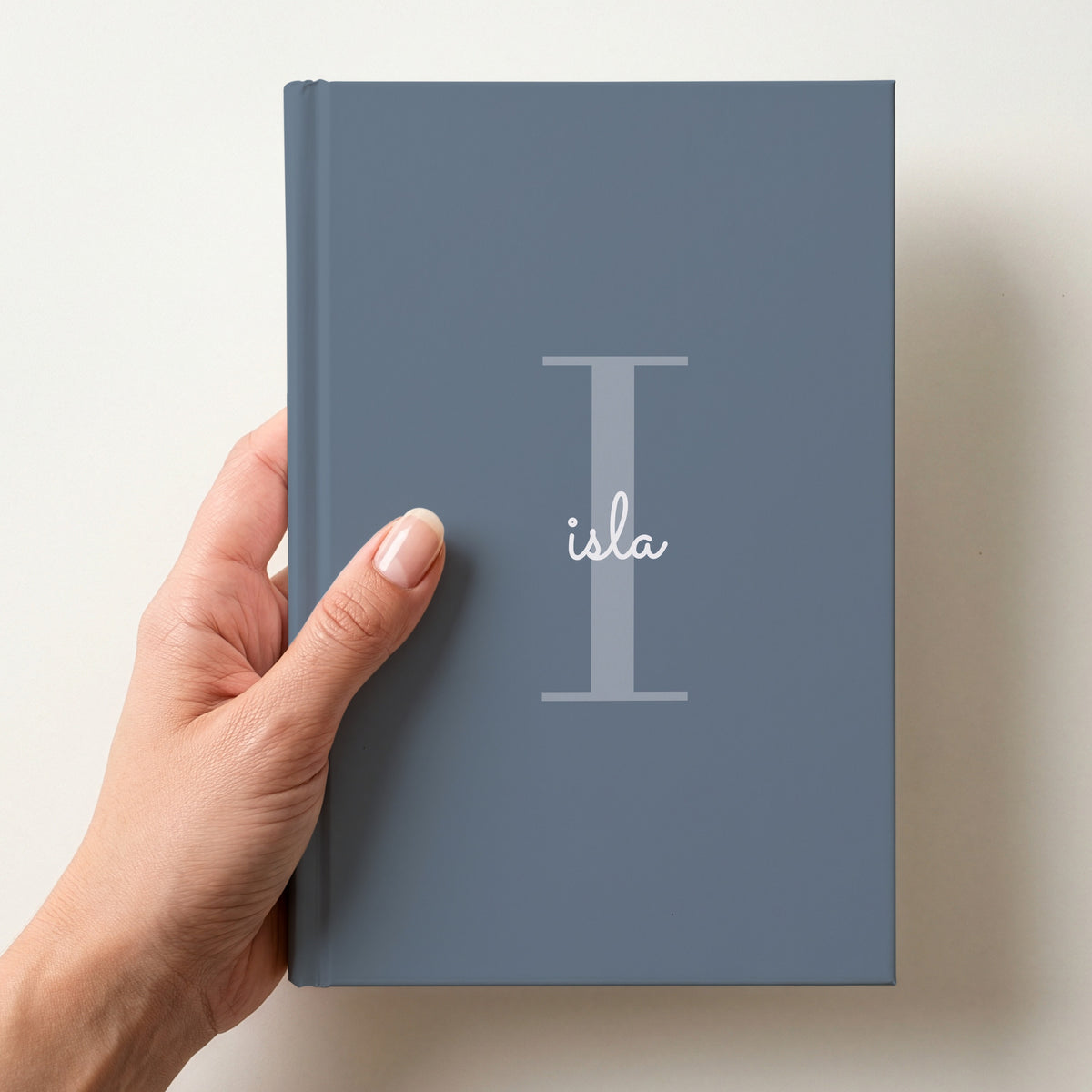 Hand holding a slate personalised journal with a large I initial and the name isla in script