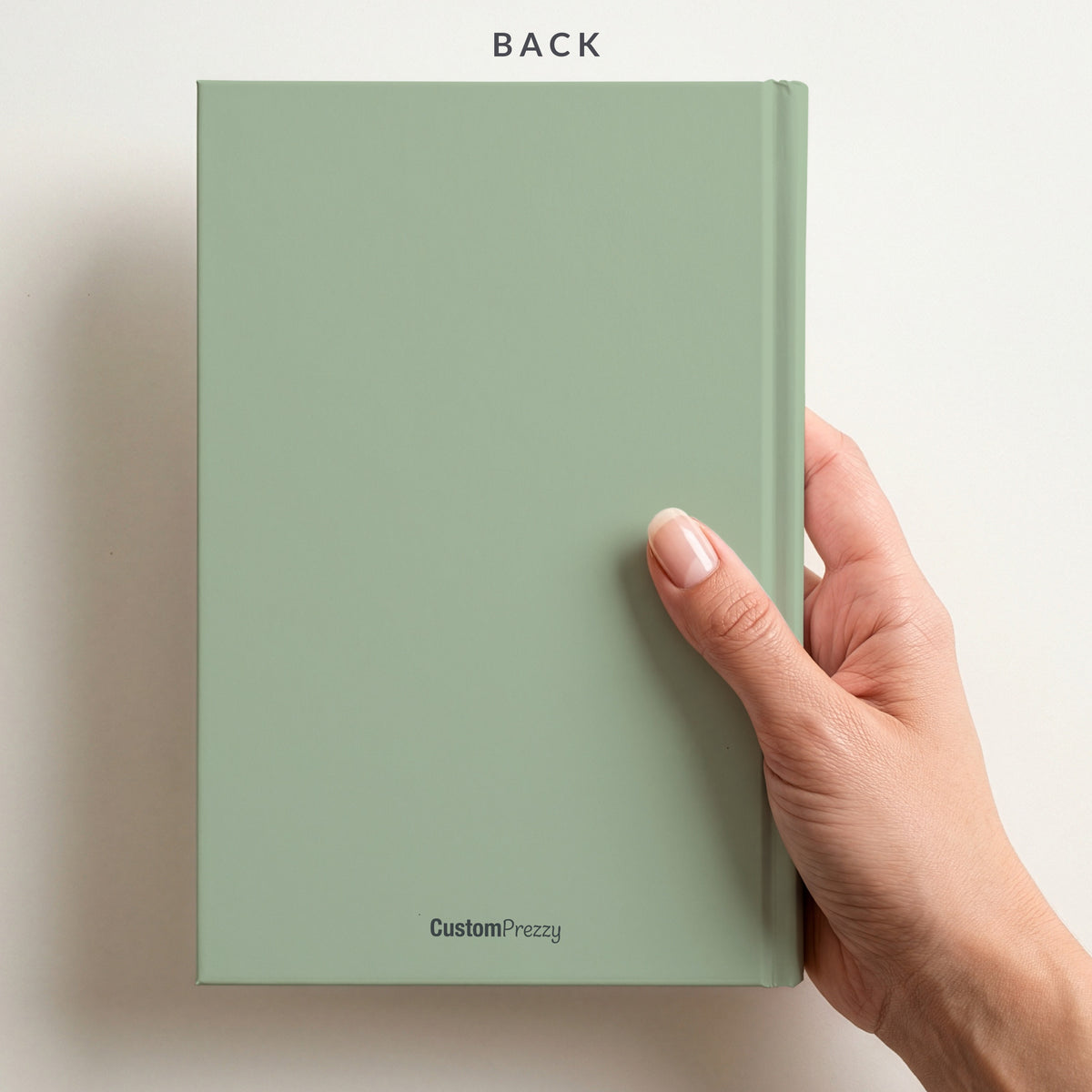 Back of the sage notebook held in a hand, with the Custom Prezzy wordmark at the foot