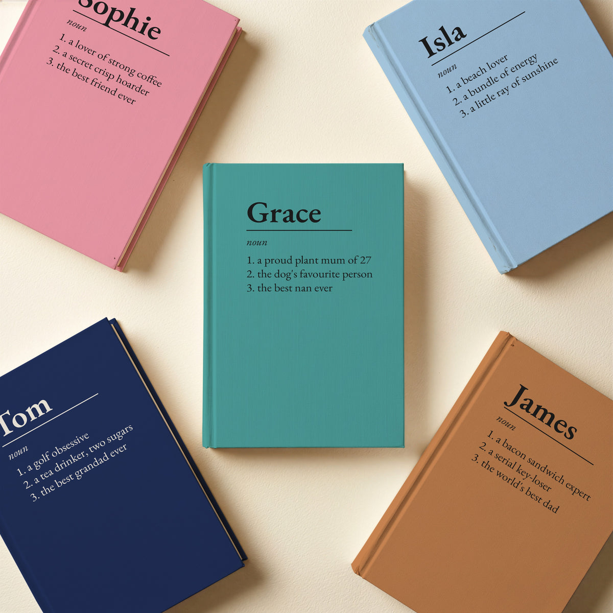 Five personalised name definition notebooks in sky blue, pink, navy, caramel and teal for Isla, Sophie, Tom, James and Grace