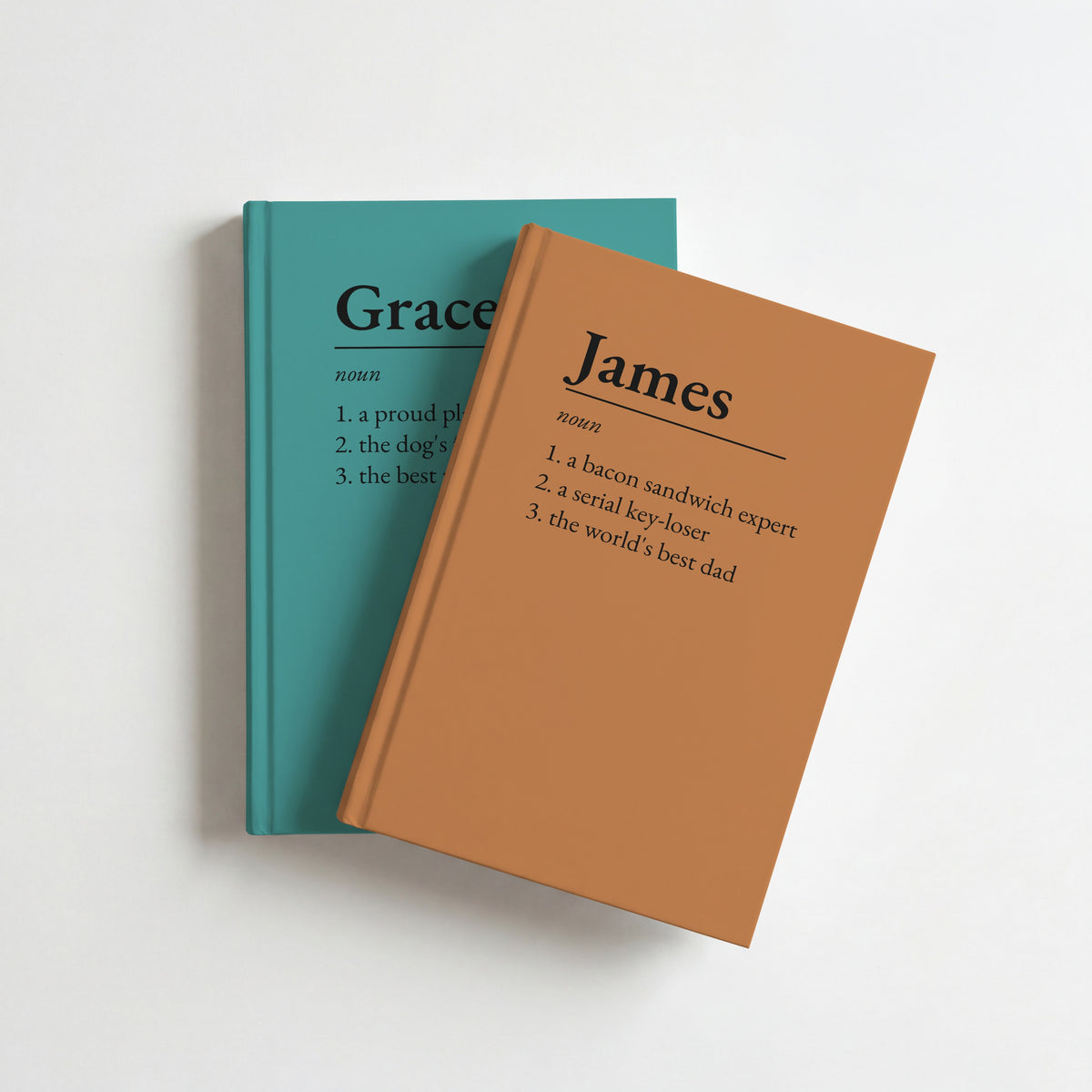 Two name definition notebooks, caramel for James on top of teal for Grace