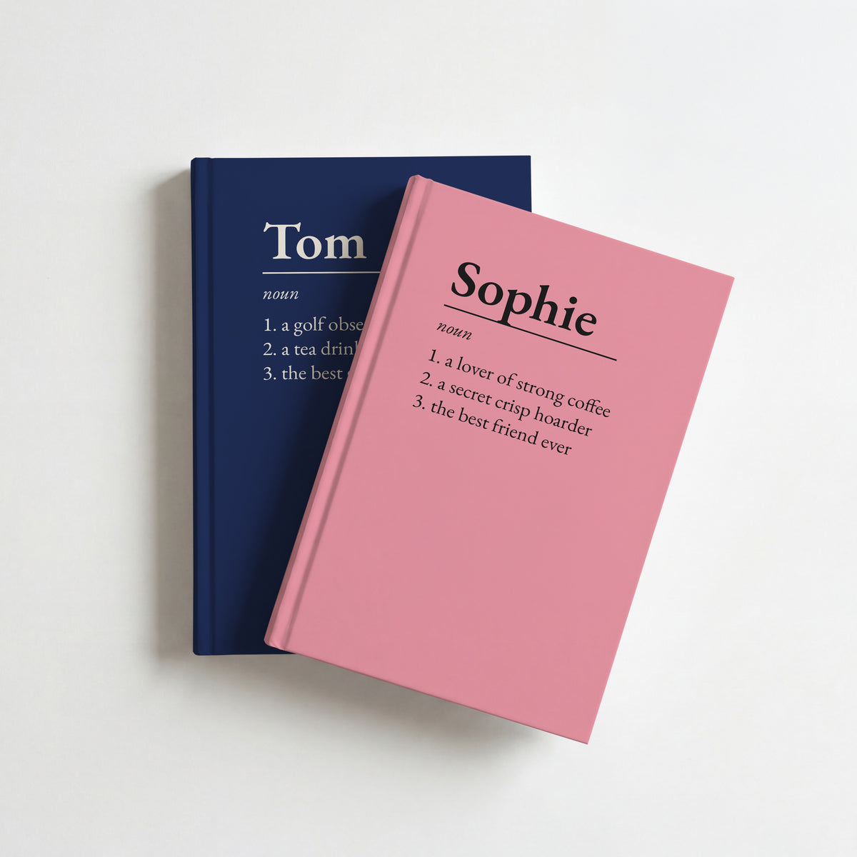Two name definition notebooks, pink for Sophie on top of navy for Tom
