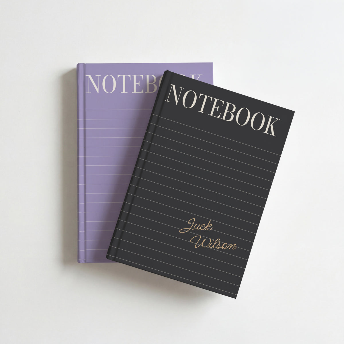 Two lined cover notebooks, charcoal with gold script on top of lilac