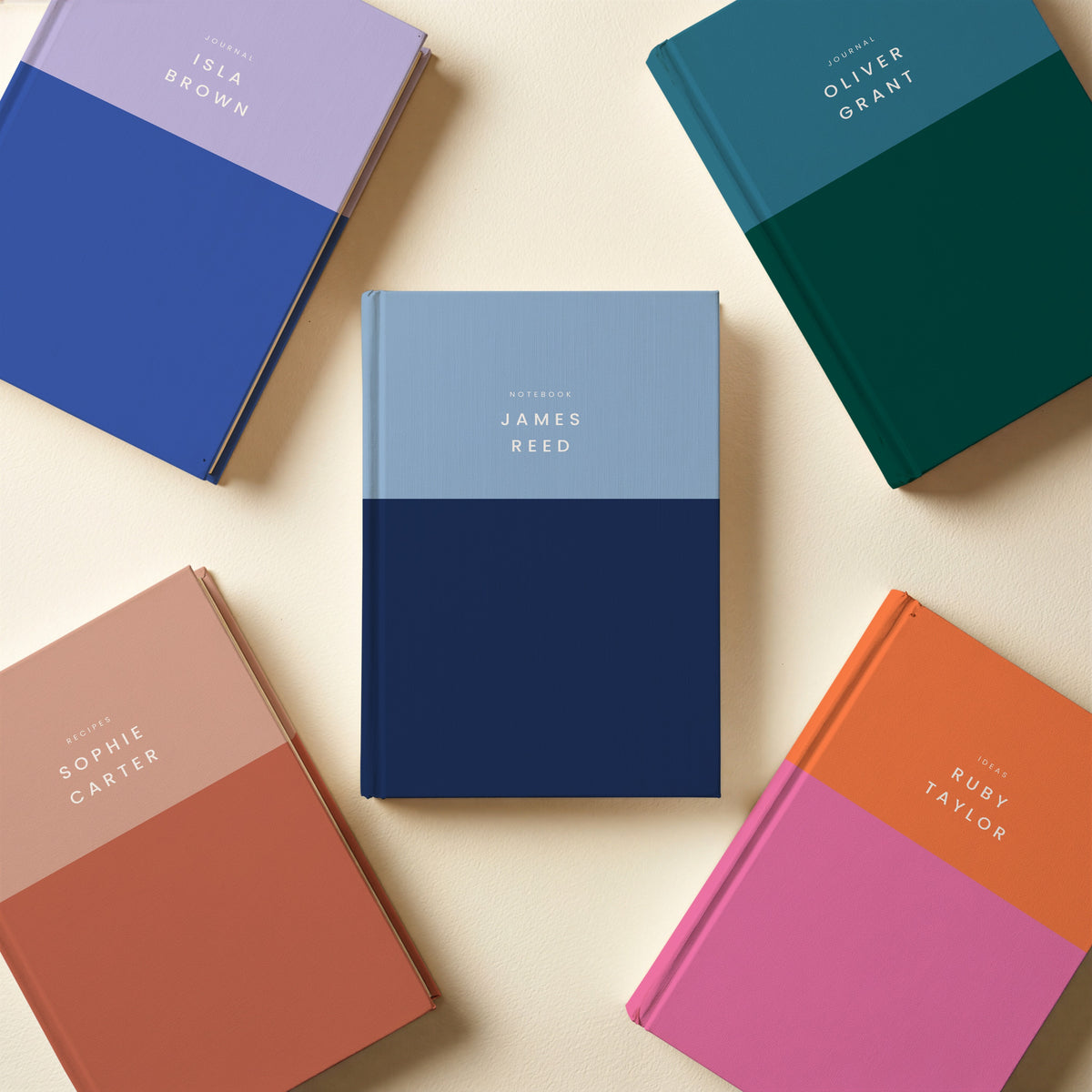 Five colour block notebooks in teal and forest, lilac and cobalt, terracotta, orange and pink, and sky and navy