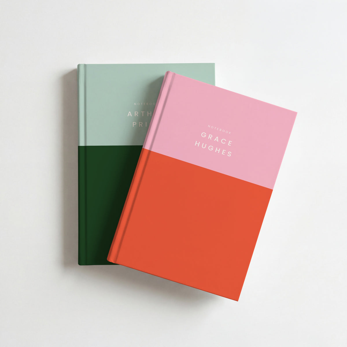 Two colour block notebooks, pink and red on top of mint and bottle green