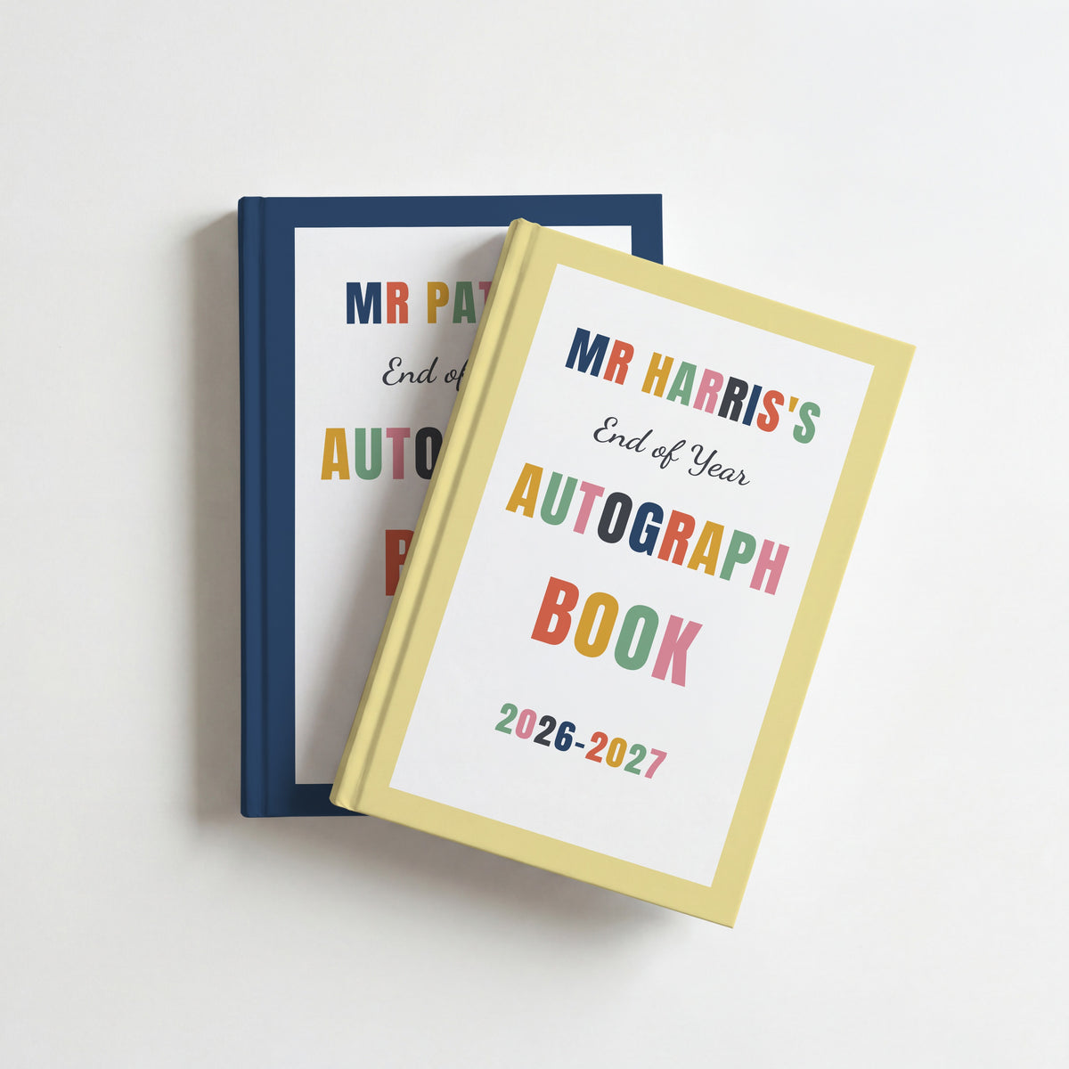 Two teacher autograph books, butter yellow for Mr Harris on top of navy for Mr Patel, both with 2026–2027